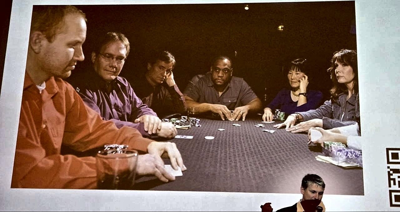 A poker table with six players, projected on a slide at the talk
