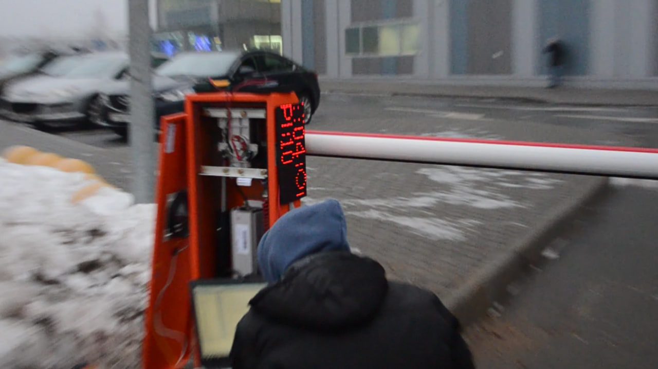 A person with a laptop at the open orange cabinet of a barrier with an LED display, in winter