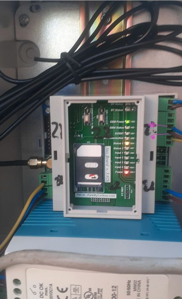 A PMCN board labelled ParkMyCarNow.com in an enclosure on a DIN rail in a site cabinet, with a power supply below
