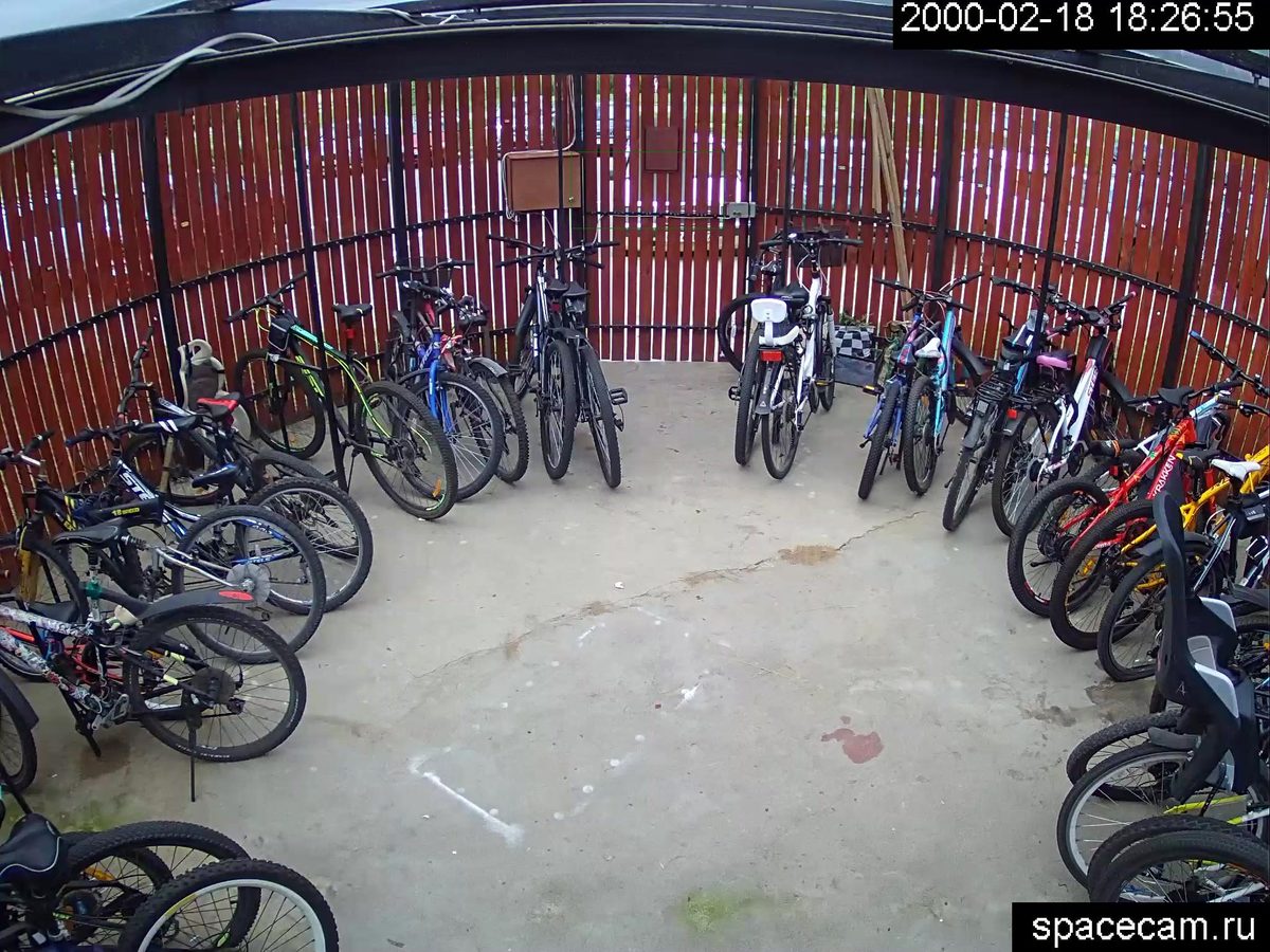 A camera frame inside a round bike garage with wooden walls, bikes standing in a circle